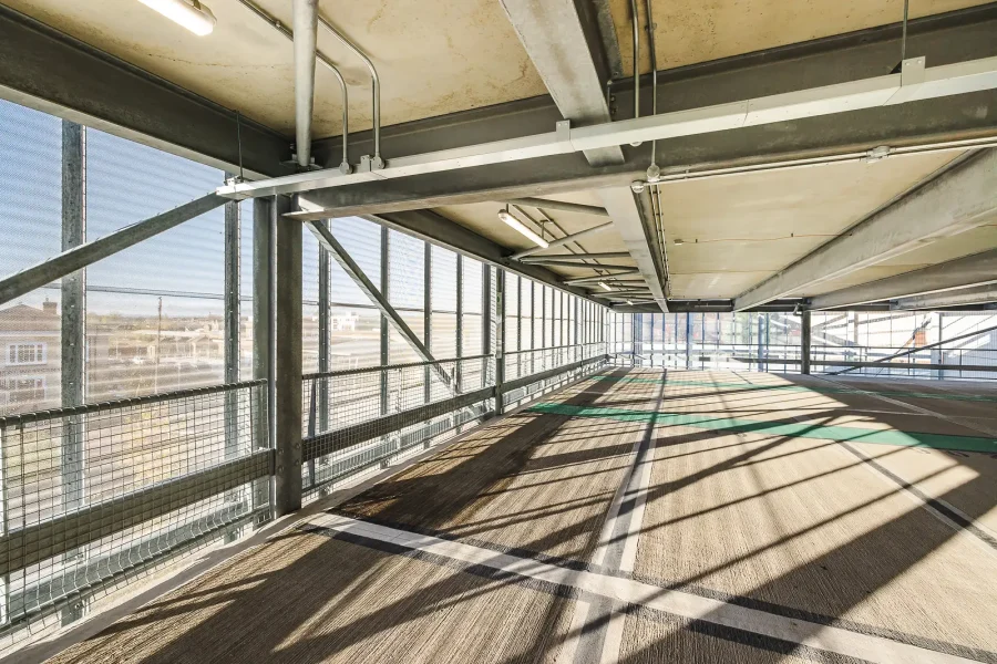 Car park interior showing steel supports, concrete decks and sunlight falling through the metal facade.