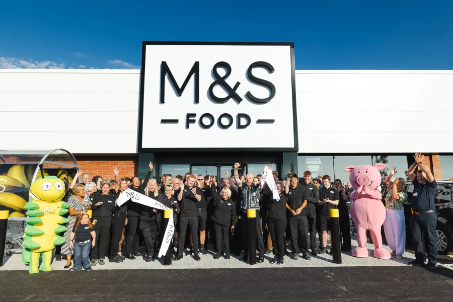 Opening-day PR photograph of colleagues cheering with the cut ribbon outside the M&S store in Poole.