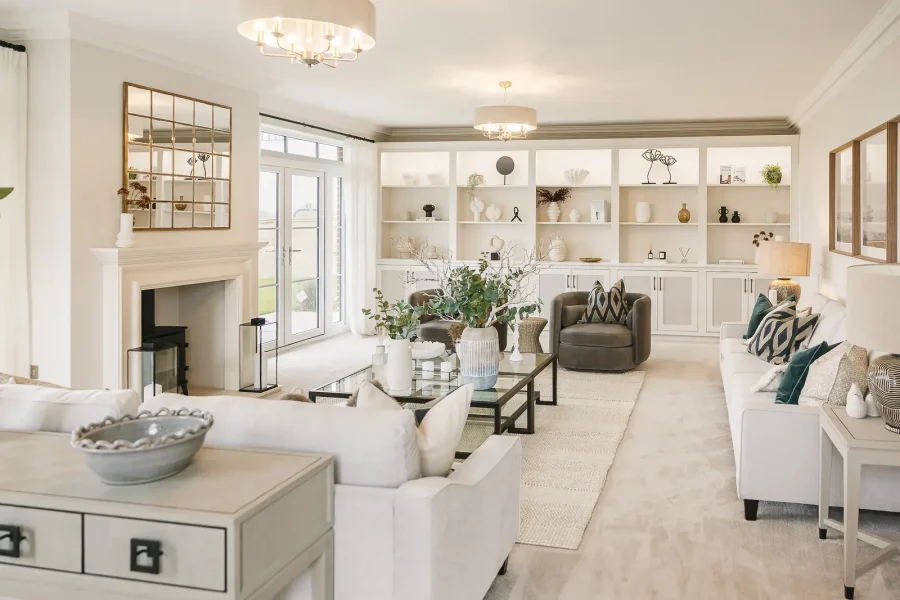 Bright living room with pale sofas, a fireplace, built-in display shelves and glazed doors to the garden.